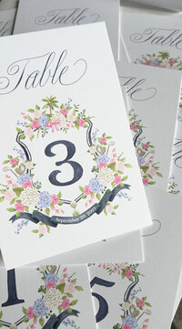 A set of 15 wedding table number cards featuring the client's wedding crest by Alicia Betz of The Welcoming District.