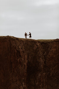 grooms walk up a cliff together