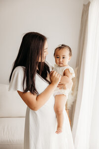 A mother holding her little baby during a family photoshoot with auckland photographer michelle kelly