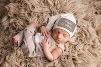 Newborn girl sweetly sleeping wearing a brown velvet headband.