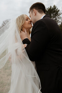 editorial portrait of groom sitting in white chair in a designer tuxedo