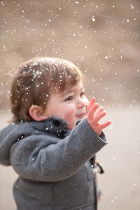 Little boy reaching out to touch snowflakes