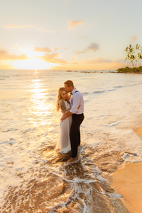 couple embrace and kiss at sunset on maui with love and water