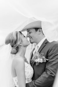 Black and white of Bride and Groom kissing under veil after wedding ceremony at The Ranch House