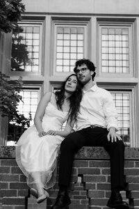 peaceful bride and groom sitting on short brick wall, black and white overlay, 35 mm wedding photography