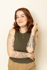 nonbinary person smiling while crossing their arms slightly