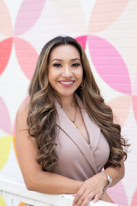 A woman in a pink dress posing next to a colorful wall at an Austin photo studio.