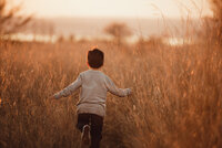 little boy running through a field
