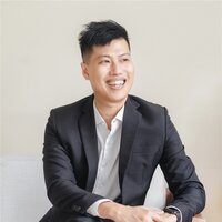 young asian man, client of Workhap, sitting wearing a grey suit and white shirt, smiling and looking into the distance