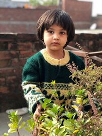 Young boy playing in a lush green forest area at an early learning center in East Dallas, part of an outdoor early childhood education program in Dallas, TX.