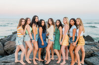 Free-spirited senior portrait photograph with the model team girls of Nicole Marie Photography. They are joyfully running down the beach in Ocean City. The ferris wheel is behind them.