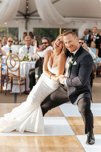 A newlywed couple laughing as they dance together.