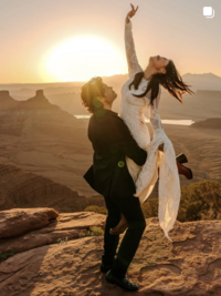 Bride and groom eloping at sunrise in Moab desert, the groom picking up the bride in a Claire Pettibone long sleeve lace gown