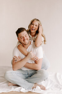 Bride with arms around groom during a studio engagement session