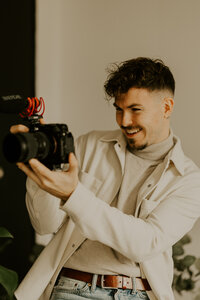 Clément, casquette sur la tête, vidéaste à the soulmate duo, examine l'écran de son appareil photo, concentré sur les réglages.