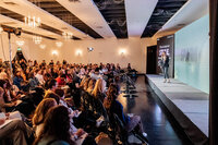 A speaker presents on stage to a full audience during a corporate event at SoHo63, a Chandler wedding and event venue. The room is filled with rows of seated guests under elegant chandeliers, showcasing SoHo63’s versatility for hosting conferences, workshops, and professional gatherings.