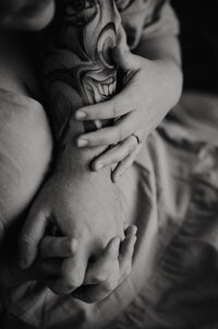 Mother holds daughter in her arms while they snuggle together, bumping noses