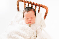 sleeping baby boy on bed with dads hand tucking him in during Springfield MO photography session