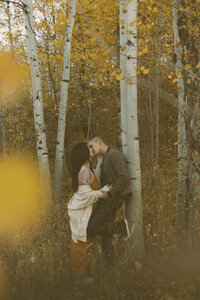 Couple snuggled up against an aspen tree in Park City, UT.