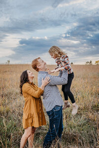 cute family in field holding little girl