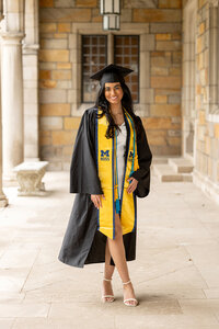 University of Michigan business graduate in cap and gown, posed for a professional portrait.