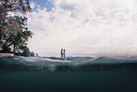 Couple standing in front of the ocean with rocks.