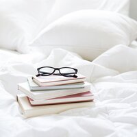 Books stacked on bed