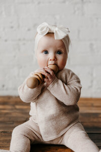 Baby wearing a cozy outfit, lying on a soft blanket with natural lighting.