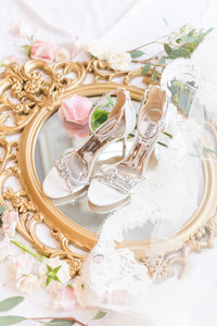 Brides wedding heels and details on top of golden mirror