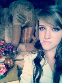 A young woman taking a selfie in front of a large wooden elephant statue at a Chinese temple