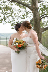Two brides walking hand in hand through a Cincinnati park during their wedding day, captured in a natural documentary style