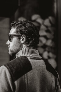 Stylish man wearing sunglasses and sweater in rustic indoor setting, photographed for branding in Breckenridge, CO.