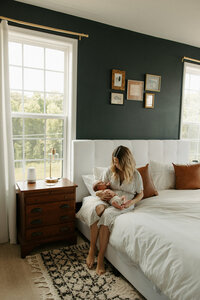 Mom and baby posing in master bedroom during RVA newborn photographers session