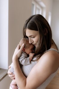 Mutter hat kleines Baby auf dem Arm und drückt es an sich ran