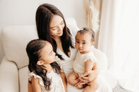 A mother holding her two little babies during a pose with michelle kelly in her auckland photography studio