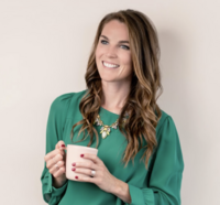 Female entrepreneur with brown hair smiling holding a coffee