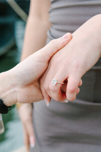 Close-up of man holding womans hand with her engagement ring on display after a Paris proposal at Passerelle Debilly near the Eiffel Tower and Palais de Tokyo.