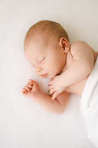 Newborn baby boy sleeps on white blanket during studio photography session in raleigh nc