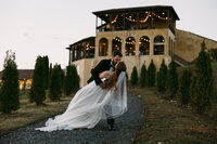 A groom dipping his bride in front of an IItialian wedding chateau
