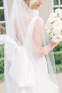 Bride holds white rose bouquet and wears veil