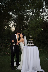 Bride and groom popping champagne at their wedding