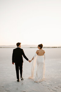 Utah Bonneville Salt Flats Elopement with bride and groom walking into the sunset.