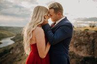 Couples photography in Rexburg Idaho. A young man is holding his girlfriend's waist, her hands around his neck. They are looking at each other and smiling.