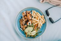 Plate of grilled fish, fries, and fresh salad, showcasing the culinary experiences curated online by Macey Johnson for hospitality brands