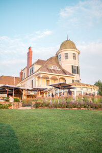 The elegant exterior of Castle Hill Inn in Newport, Rhode Island, showcasing its distinctive turret and classic shingle-style architecture bathed in golden sunset light — an iconic setting for upscale coastal weddings.