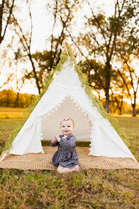 first birthday photoshoot of a little girl with a white boho tent