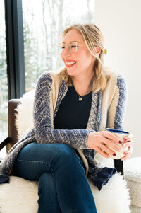 A woman in a chair, sipping coffee, representing a psychotherapist in a warm and inviting office environment.