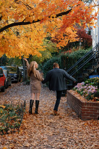 A couple walking together and kicking leaves