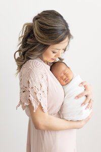 new mom in beautiful dress snuggling baby boy for newborn session