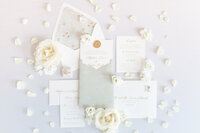 bright light and airy wedding photo of bride  details wedding invitation flatlay shot flowers ring